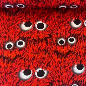 Könnte beinhalten: Roter Stoff mit einem sich wiederholenden Muster aus weißen Glitz Augen. Der Stoff hat eine flauschige Textur.