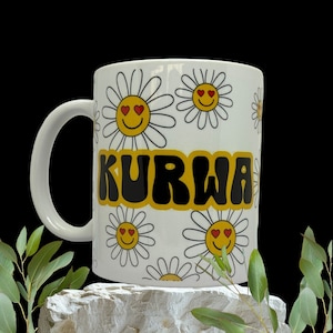 Könnte beinhalten: Eine weiße Keramiktasse mit einem schwarzen und gelben Design, das das Wort "KURWA" und ein Muster aus gelben Gänseblümchen mit roten Herzen als Augen zeigt.