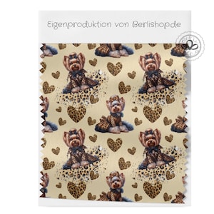 Könnte beinhalten: Stoffmuster mit einem sich wiederholenden Muster von Yorkshire Terriern in Leoparden-Outfits und Schleifen, durchsetzt mit Leopardenherzen auf beigem Hintergrund. Der Text "Eigenproduktion von Berlishop.de" steht oben.
