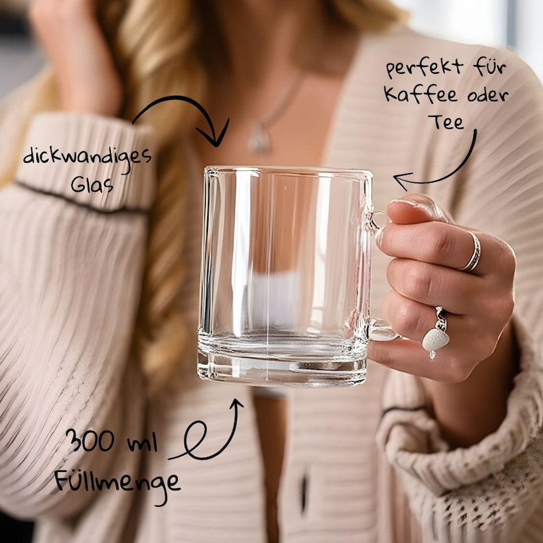 May include: A clear glass mug with a handle, designed for coffee or tea. The mug has a thick-walled design and holds 300 ml. The mug is held by a person wearing a cream-colored sweater.