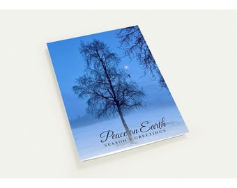 May include: A rectangular greeting card featuring a winter scene with a bare tree against a deep blue twilight sky and a snow-covered field. The text Peace on Earth and SEASON'S GREETINGS is printed in a dark blue script and sans-serif font.