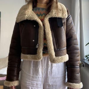 women's sheepskin jacket, brown aviator jacket, B3 bomber jacket, vintage leather jacket, distressed sheepskin bomber, lambskin winter coat, shearling leather jacket, fur collar jacket, winter bomber jacket, real leather bomber, women's flight jacket, warm shearling coat, classic aviator style, cozy winter outerwear, retro bomber jacket, women's vintage coat, shearling jacket for her, leather coat with fur cuffs, WWII pilot jacket, brown lambskin bomber, winter coat gift idea