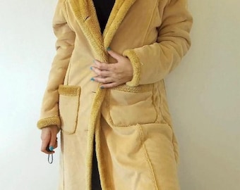 May include: A long, tan suede coat with a faux fur lining. The coat has a button closure and two large pockets.