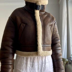 women's sheepskin jacket, brown aviator jacket, B3 bomber jacket, vintage leather jacket, distressed sheepskin bomber, lambskin winter coat, shearling leather jacket, fur collar jacket, winter bomber jacket, real leather bomber, women's flight jacket, warm shearling coat, classic aviator style, cozy winter outerwear, retro bomber jacket, women's vintage coat, shearling jacket for her, leather coat with fur cuffs, WWII pilot jacket, brown lambskin bomber, winter coat gift idea