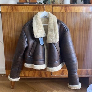 shearling aviator jacket, women's B3 bomber, real lambskin leather, vintage shearling coat, fur collar bomber jacket, distressed brown coat, leather pilot jacket women, sheepskin leather outerwear, bomber jacket with cuffs, brown flight jacket, winter leather jacket, cozy fur-lined jacket, lambskin aviator bomber, 1940s flight coat, warm women's bomber, classic leather trench, pilot-style winter jacket, authentic sheepskin coat, fur cuff leather jacket, cold weather outerwear, gift for her