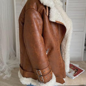 women’s brown bomber jacket, shearling lambskin aviator coat, distressed leather winter jacket, vintage RAF flight bomber, fur-lined collar coat women, B3 pilot style bomber jacket, warm sheepskin leather outerwear, WWII inspired winter coat, retro lambskin shearling bomber, women’s classic RAF jacket, soft fur collar leather coat, vintage flight style bomber, handmade distressed leather jacket, cozy winter pilot coat, brown winter leather bomber, real sheepskin flying coat for women