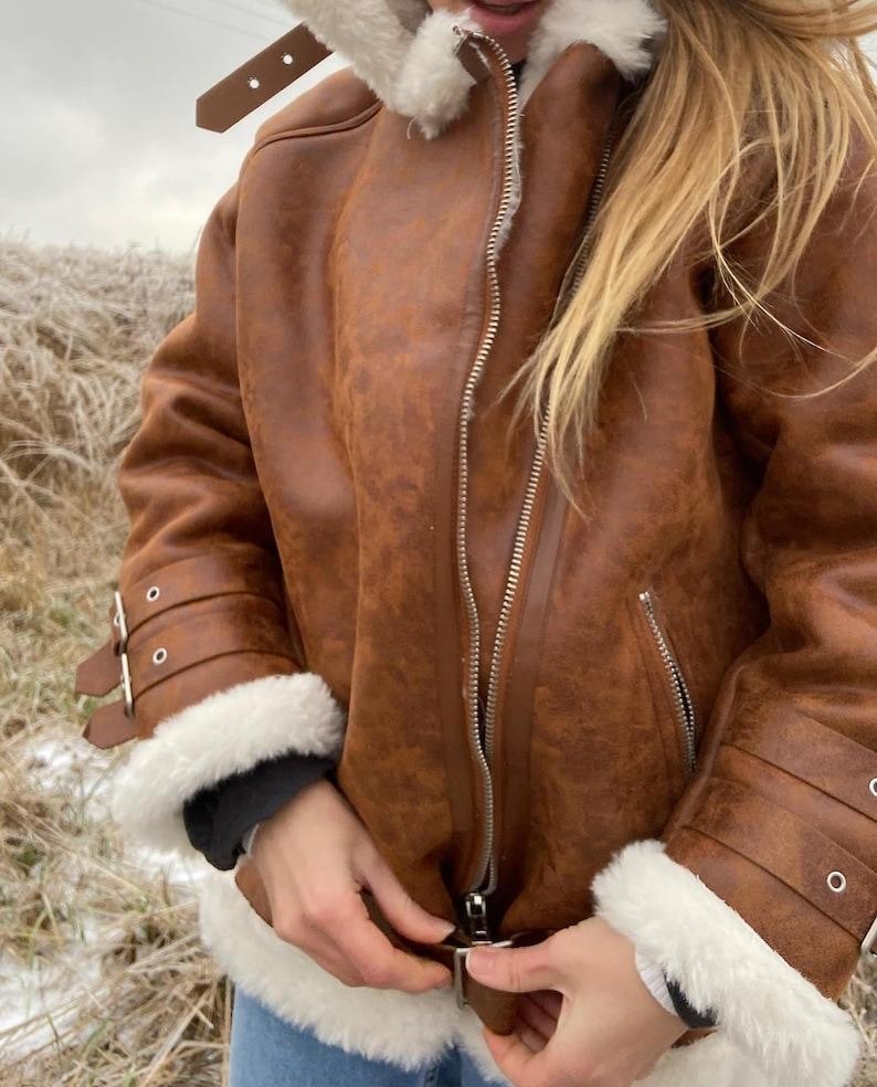 women’s sheepskin aviator jacket, brown B3 bomber coat, RAF vintage flight jacket, distressed lambskin shearling, winter leather bomber coat, real fur collar jacket, warm shearling outerwear, retro aviator leather coat, brown shearling bomber jacket, WWII pilot style coat, lambskin flight bomber, women’s winter aviator coat, soft sheepskin leather jacket, fur-lined cuffs coat, classic RAF B3 jacket, leather flying bomber women, handmade sheepskin winter jacket, vintage lambskin coat women