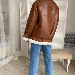 shearling bomber jacket, women’s distressed aviator coat, vintage lambskin winter jacket, B3 flight bomber women, RAF style pilot coat, fur collar winter outerwear, warm sheepskin jacket for her, handmade lambskin bomber, real leather flight jacket, WWII inspired women’s bomber, classic brown shearling coat, cozy pilot style jacket, fur-lined cuffs leather coat, brown winter bomber jacket, women’s warm aviator outerwear, timeless shearling leather coat, vintage pilot jacket women