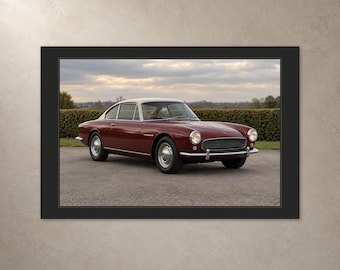 May include: A framed print featuring a maroon vintage coupe with a white roof, chrome bumpers, and round headlights. The car is parked on an asphalt surface with a green hedge and a cloudy sky in the background, presented in a black frame.
