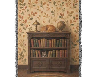 May include: A woven throw blanket featuring a detailed scene of a dark wood bookcase filled with books, a sleeping orange cat on top, a small kitten on a shelf, a lamp, and a globe, set against a wall with a leafy botanical pattern.