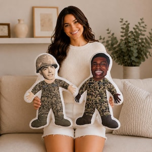 May include: Two custom-shaped plush pillows featuring printed images of soldiers in camouflage uniforms. One pillow shows a soldier wearing a helmet with the name Drager, and the other shows a smiling soldier with the name Cale on the uniform.