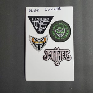 May include: Four embroidered patches featuring the text "Blade Runner", "Rep Detect 26354", "Genetic Replicants Tyrell More Human Than Human", and "Spinner".