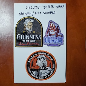 May include: Three embroidered patches featuring Star Wars characters. The first patch is black with a Guinness logo and the text "Obi-Wan Kenobi" and "Alec Guinness". The second patch is purple with the text "Rancho Obi-Wan" and "Member 2015". The third patch is orange with a Stormtrooper and the text "501st Legion Honorary Member" and "These aren't the Droids we're looking for".