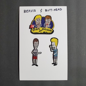 Op de afbeelding: Drie geborduurde patches met de cartoonfiguren Beavis en Butt-Head. De eerste patch toont de gezichten van Beavis en Butt-Head met de tekst "Beavis and Butt-Head" en "MTV" eronder. De tweede en derde patches tonen Beavis en Butt-Head staand met hun kenmerkende uitdrukkingen.
