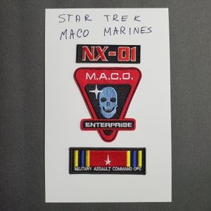 May include: Three embroidered patches featuring the Star Trek: Enterprise logo, the words "M.A.C.O." and a skull, and the words "Military Assault Command Ops".
