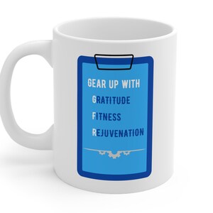May include: White ceramic mug with a blue and white graphic of a clipboard with the text "Gear Up With Gratitude Fitness Rejuvenation".