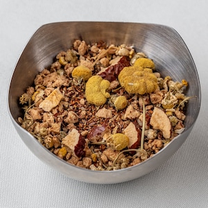 May include: A silver bowl filled with a blend of loose leaf tea. The tea includes dried fruit, flowers, and herbs.