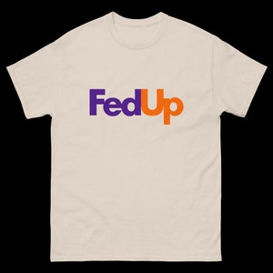 May include: Cream-colored t-shirt with the word "FedUp" printed on the front. The word "Fed" is in purple, and "Up" is in orange, mimicking a well-known logo. The shirt has a crew neck and short sleeves.