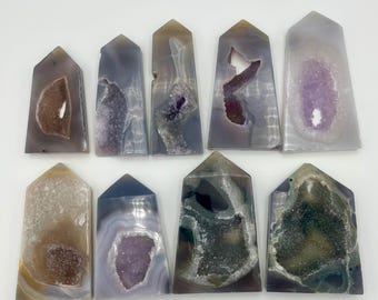 May include: Ten agate crystal points with various colors and patterns, including purple, brown, white, and green. Each point has a unique shape and a hollowed-out center.