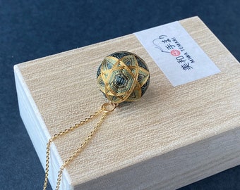 Japanese temari pendant with geometric design, on long chain necklace. Traditional Japanese silk embroidery. Colors: green/yellow/gold.