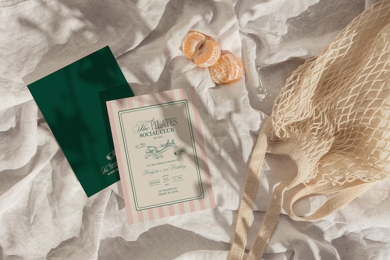 Puede incluir: Vista a&eacute;rea de una tarjeta verde y una invitaci&oacute;n a rayas rosas con el texto "The Pilates Social Club". Una bolsa de red y dos gajos de mandarina descansan sobre una superficie blanca texturizada.