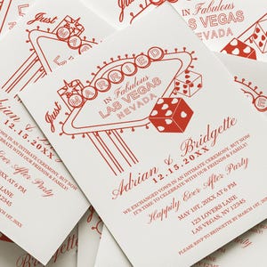 May include: Red and white wedding invitation with a Vegas-themed design. The invitation features a red and white illustration of the iconic "Welcome to Fabulous Las Vegas" sign with dice and hearts. The text on the invitation reads "Just Married in Fabulous Las Vegas, Nevada" and includes the names Adrian and Bridgette and the date 12.15.20XX.