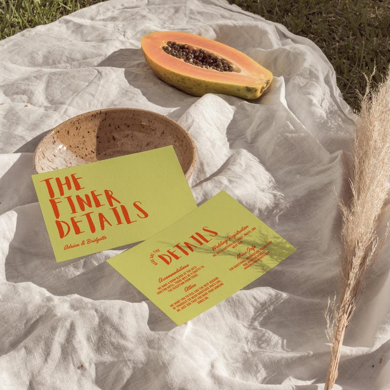 May include: A still-life image featuring two lime green cards with red text that reads "THE FINER DETAILS" and "DETAILS". A halved papaya, a speckled ceramic bowl, and dried grass are also present. The cards appear to be wedding invitations.
