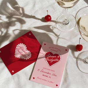 May include: Pink and red save the date card with a heart design and the text "We're getting married! Adrian & Bridgette Save our date 15 December 20xx Miami, FL Formal invitation to follow!"
