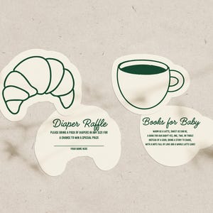 May include: Four cream-colored paper cutouts with dark green outlines. One is a croissant, another a coffee cup, and two with text. The text reads "Diaper Raffle" and "Books for Baby". The diaper raffle cutout has a space for a name.