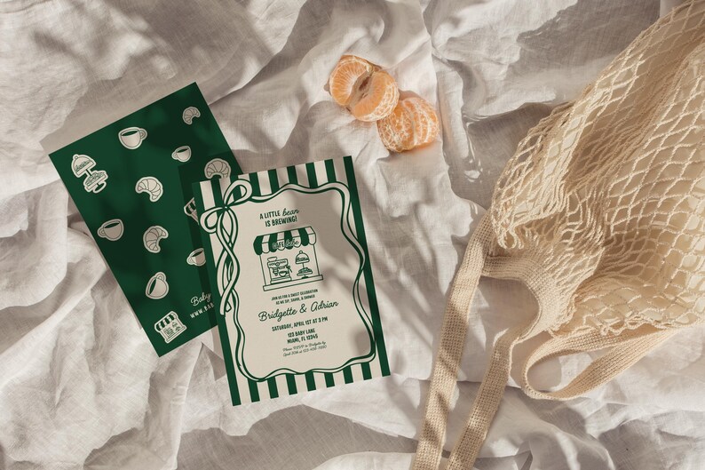 May include: An overhead shot features a green and white invitation with the text "A little bean is brewing" and a matching green card with coffee and croissant illustrations. A string bag and mandarin orange slices are also present.