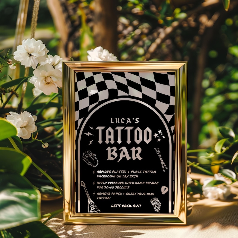May include: A gold-framed sign with a black and white checkered background. The sign says "Luca's Tattoo Bar" with instructions on how to apply temporary tattoos. The sign has a rock and roll theme with images of a guitar, microphone, and lightning bolt.