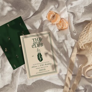 K&ouml;nnte beinhalten: Eine Einladung f&uuml;r "The Golf Club" mit einer Golfbag-Illustration und einer dunkelgr&uuml;nen Karte mit Golffiguren. Die Einladung ist f&uuml;r Adrians 30. Geburtstag. Ein Netzbeutel und zwei Mandarinenspalten sind ebenfalls im Bild.