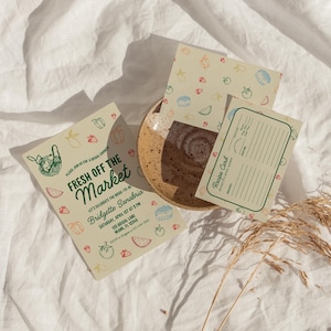 May include: A green and white invitation card with a hand-drawn illustration of a basket of produce. The text reads "Fresh Off The Market" and includes details for a bridal shower. A recipe card with a similar design is also included.