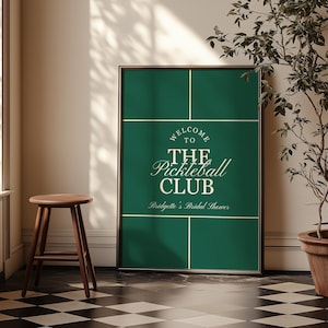 May include: A framed sign with a dark green background and white lines, resembling a pickleball court. The text reads "WELCOME TO THE Pickleball CLUB" and "Bridgette's Bridal Shower."