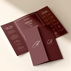 Könnte beinhalten: Burgunderfarbene Hochzeitseinladung mit dreifachem Design. Die Einladung zeigt die Namen "Adrian Grey" und einen Zeitplan der Ereignisse. Die Vorderseite der Einladung trägt die Buchstaben "A" und "B" in einer Schreibschrift.