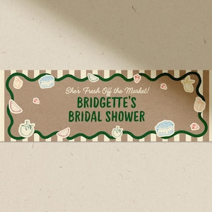 May include: A rectangular invitation with a brown background and the text "She's Fresh Off the Market! Bridgette's Bridal Shower." The invitation has a green wavy border and is decorated with illustrations of fruits and vegetables.