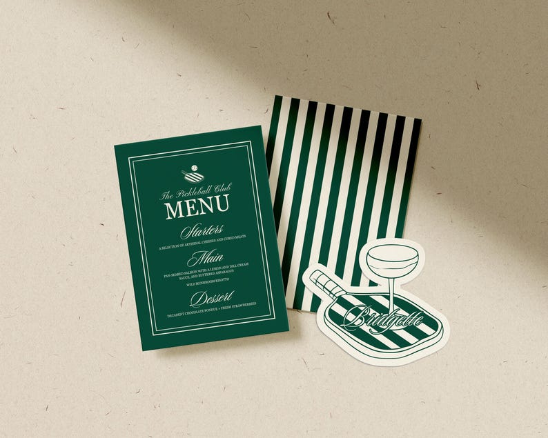 May include: A dark green menu card with white text and a white border. The menu is for "The Pickleball Club" and lists starters, main, and dessert options. A sticker with a pickleball paddle and a cocktail glass is also present.