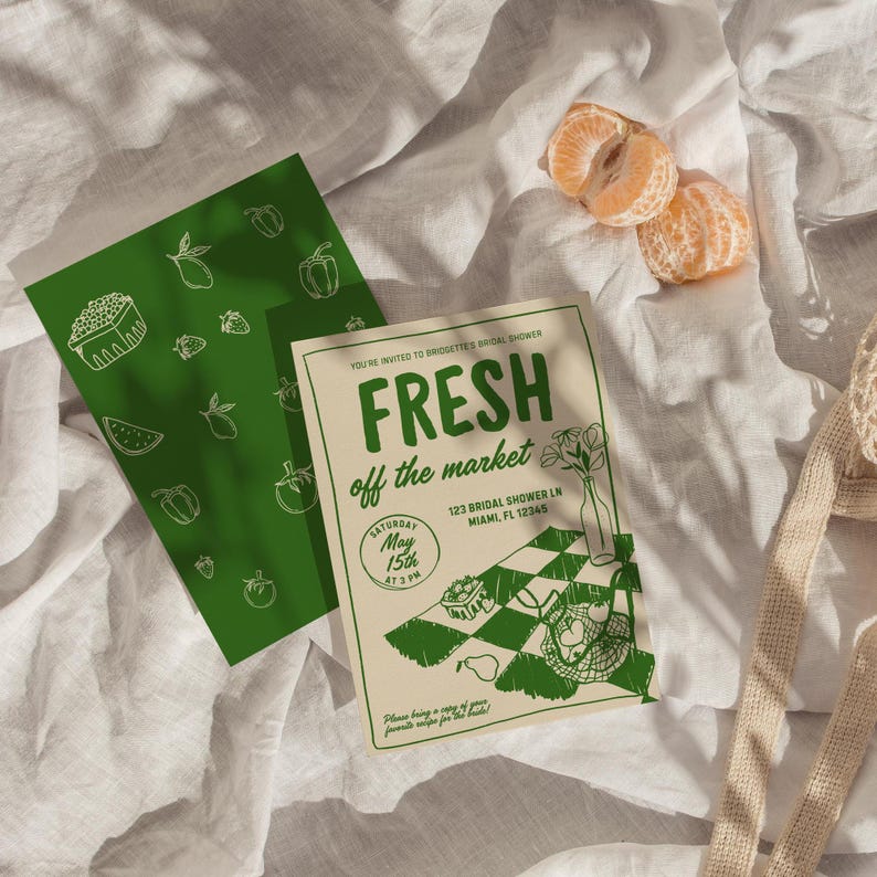 Op de afbeelding: Twee groene en witte bruidsdouche-uitnodigingen met de tekst "FRESH off the market". E&eacute;n uitnodiging heeft een patroon van groenten en fruit. De andere heeft een geblokt tafelontwerp met een vaas bloemen en een fruitmand. Twee geschilde mandarijnsegmenten zijn ook zichtbaar.