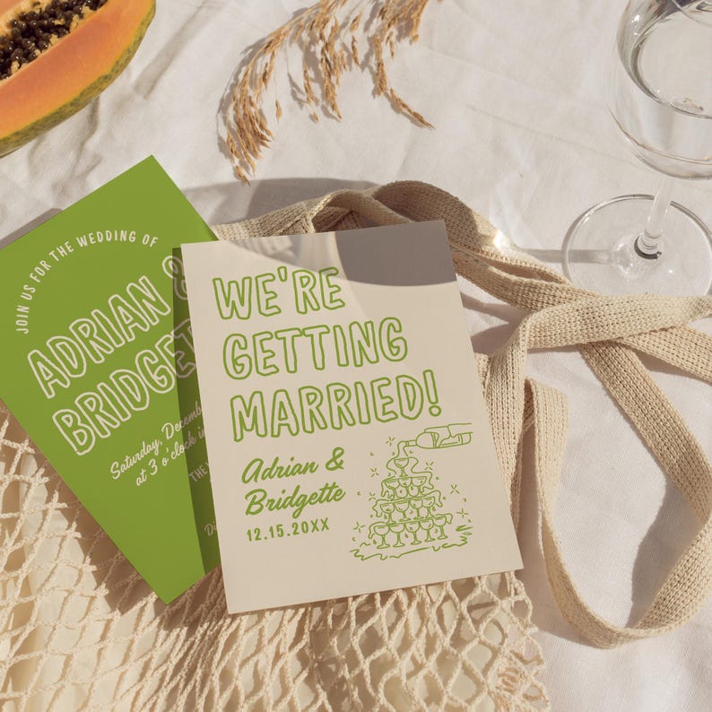 May include: A light brown card with green text announcing a wedding. The text reads "We're Getting Married!" with the couple's names, Adrian & Bridgette, and the date 12.15.20XX. A green illustration of a champagne tower is to the right of the text.