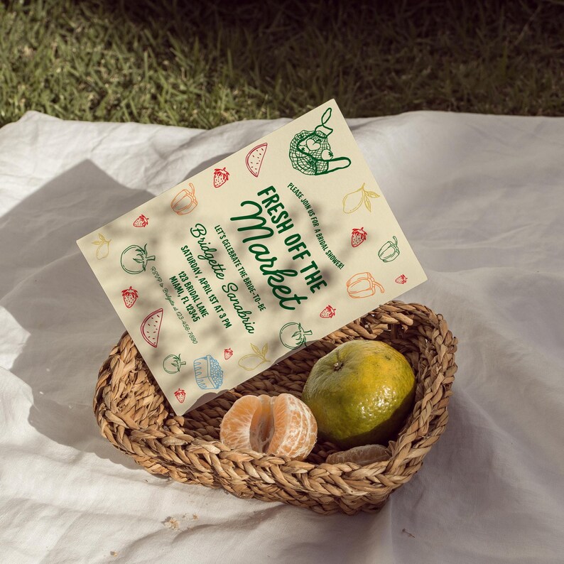 May include: A cream-colored invitation card with green and red text that reads "Fresh Off The Market" and "Bridgette Sanabria". The invitation is for a bridal shower and includes the date, time, and location. The card is decorated with drawings of fruits and vegetables.