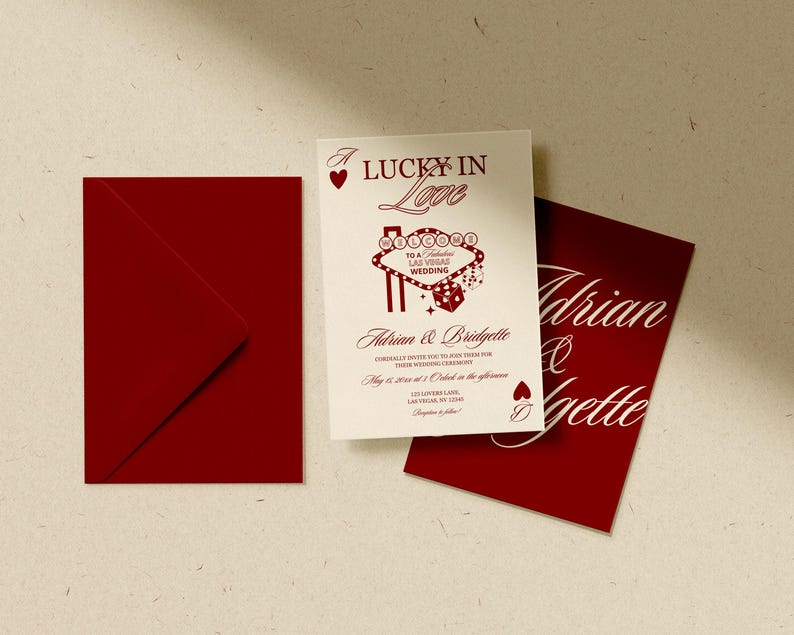 Puede incluir: Un conjunto de invitaciones de boda con un sobre rojo, una tarjeta de invitaci&oacute;n blanca con texto rojo y una tarjeta roja con escritura blanca. La invitaci&oacute;n dice "Lucky in Love" e incluye los nombres Adrian & Bridgette.