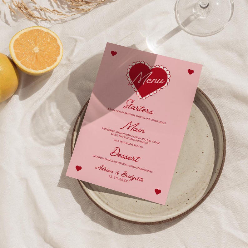 May include: A pink menu card with a red heart design and the text "Menu" inside the heart. The menu lists "Starters", "Main", and "Dessert" with descriptions for each course. The bottom of the card has the names "Adrian & Bridgette" and the date "12.15.20XX".