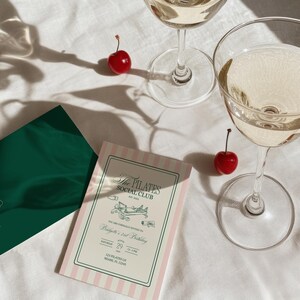 Puede incluir: Dos copas de champ&aacute;n llenas de una bebida clara, junto con dos cerezas rojas y dos tarjetas de invitaci&oacute;n. Una tarjeta es verde, la otra es rosa y blanca a rayas con el texto: "The Pilates Social Club".