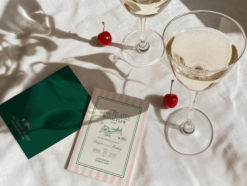 Puede incluir: Dos copas de champ&aacute;n llenas de una bebida clara, junto con dos cerezas rojas y dos tarjetas de invitaci&oacute;n. Una tarjeta es verde, la otra es rosa y blanca a rayas con el texto: "The Pilates Social Club".