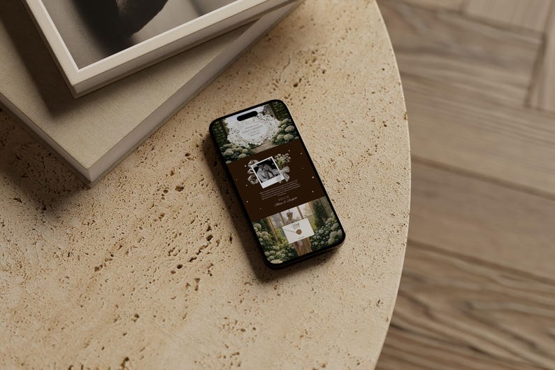May include: A smartphone displaying a website design with a nature theme, featuring images and text. The phone rests on a textured, light-colored surface, next to a stack of books with a white frame.