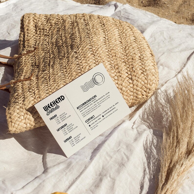 May include: A white card with black text listing weekend details for a beach getaway. The card includes a schedule of events for Friday, Saturday, and Sunday, along with accommodation and contact information. The card is lying on a white fabric surface with a woven straw bag and dried grass.