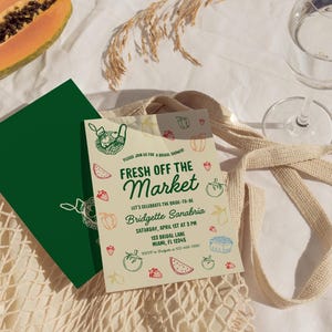 May include: A light yellow bridal shower invitation with green, red, and blue illustrations of fruits and vegetables. The text reads "Fresh Off The Market" and includes the bride-to-be's name, date, time, and location.