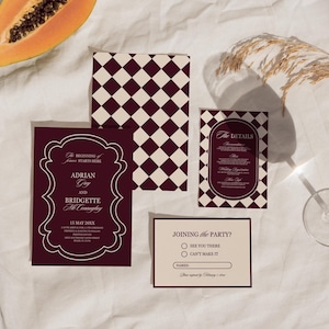 May include: A collection of wedding stationery in burgundy and cream, including invitations and RSVP cards. The invitation features the names "Adrian Gray" and "Bridgette McConaghey" with the date "15 May 20XX". A half papaya and a glass are also in the image.
