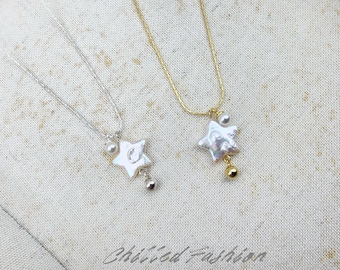 Puede incluir: Dos collares con colgantes de perlas blancas en forma de estrella. Uno tiene una cadena plateada con una pequeña cuenta redonda plateada, y el otro una cadena dorada con una pequeña cuenta redonda dorada. Ambos incluyen una perla redonda.