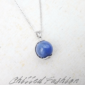 May include: A silver necklace with a round, blue gemstone pendant. The pendant is encased in a silver setting and hangs from a delicate chain. The text "Chilled Fashion" is at the bottom of the image.